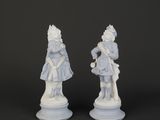 two white figurines of a man and a woman on a pedestal