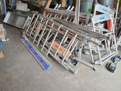 a pile of ladders in a garage next to a pile of boxes