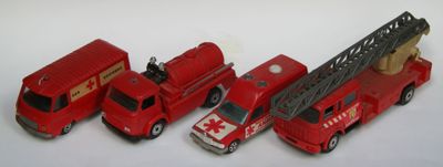 Plusieurs camions de pompiers miniatures sont alignés en rang sur une surface blanche