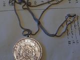 une pièce d'argent attachée à une chaîne, posée sur un morceau de papier