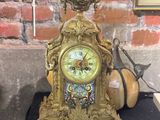 une horloge dorée posée sur une table noire devant un mur de briques