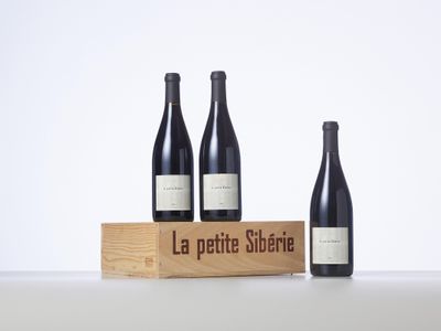 three bottles of wine sit in front of a wooden box