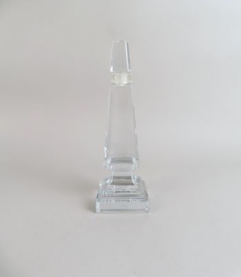 un bougeoir en verre transparent posé sur une surface blanche