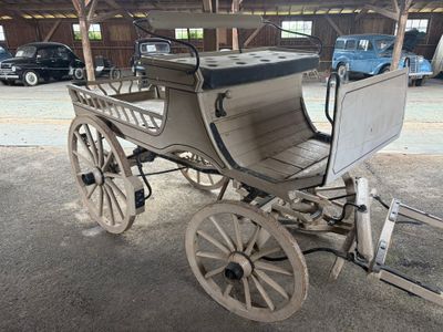un cheval et une calèche dans une grange, avec une voiture en arrière-plan