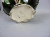 a green vase with flowers on it sitting on a table