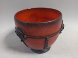 a red and black bowl sitting on a white surface