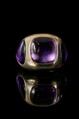 a close up of a gold ring with a purple stone