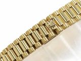a gold bracelet with a diamond on it on a white surface