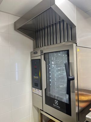 four en acier inoxydable dans une cuisine professionnelle dont les murs sont recouverts de carrelage blanc