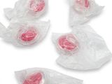 plusieurs bonbons en plastique emballés dans des sachets en plastique, posés sur une surface blanche
