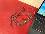 a laptop with a cable connected to it on a red surface