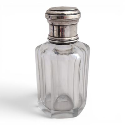 a glass bottle with a silver lid on a white surface
