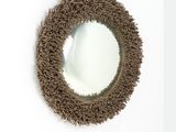 un miroir rond accroché à un mur blanc, avec un cadre marron