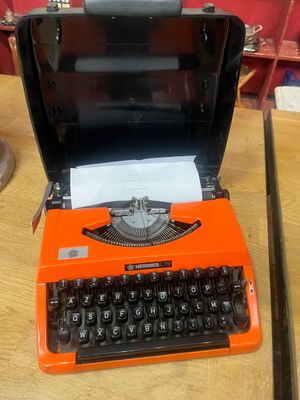 an orange typewriter sitting on a wooden table