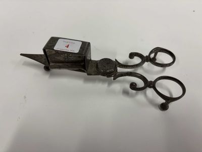 une paire de ciseaux anciens en fer posés sur une surface blanche