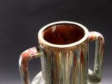 a close up of a vase with a handle on a table