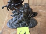 une statue en bronze représentant une femme et un chien, posée sur une table