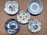 four blue and white plates with flowers and birds on them