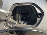 a person standing next to a car with an electric plugged in it