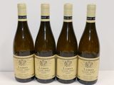 quatre bouteilles de vin blanc sont alignées sur une table