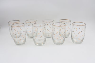 six verres parsemés de points dorés sont alignés sur une surface blanche