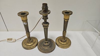 trois bougeoirs anciens en laiton exposés dans une vitrine