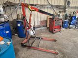 une grue qui se trouve dans un garage, à côté de quelques fûts