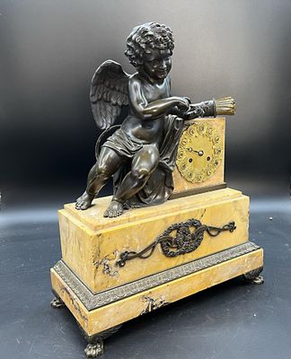 une figurine antique en bronze représentant un ange avec une horloge