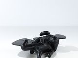 une sculpture noire représentant une abeille posée sur une surface blanche
