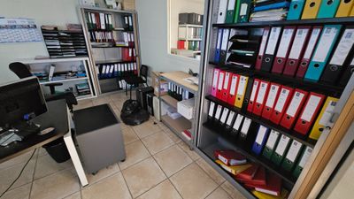 une pièce où se trouvent de nombreux classeurs et un ordinateur posé sur le bureau