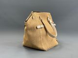 le petit sac tissé est posé sur une surface grise