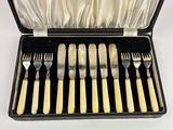 six forks and a knife in a case