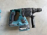 a close up of a corded drill on the floor next to a hammer