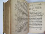someone is holding an open book in their hand on a table