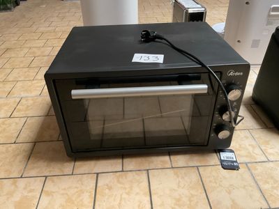 un micro-ondes noir posé sur un sol carrelé, à côté d'une poubelle