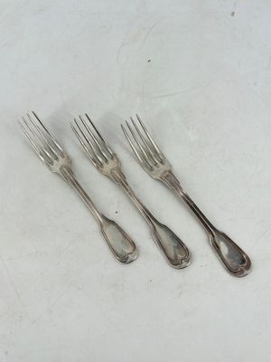 trois fourchettes et un couteau sont posés sur une surface blanche