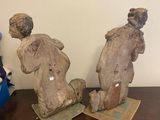 two statues of a man and a woman sitting on top of a wooden table