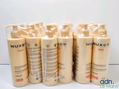 six flacons de lait solaire Nuxe posés sur une surface blanche