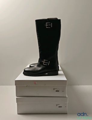 une paire de bottes noires posée sur une pile de cartons blancs