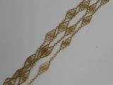 a close up of a gold chain bracelet on a white surface