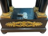 a black and gold clock with a key on top of it