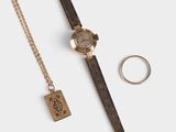 un gros plan d'une montre et d'une bague posées sur une surface blanche