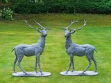 deux statues de cerfs posées sur un socle dans l'herbe