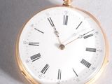 a gold pocket watch with roman numerals on the face