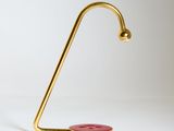 une lampe de bureau dorée sur laquelle se trouve un bouton rouge