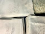 three white towels with embroidered monograms on them are on a table