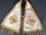 a close up of a white shawl with a cross on it
