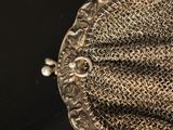 a close up of a metal mesh purse on a black surface