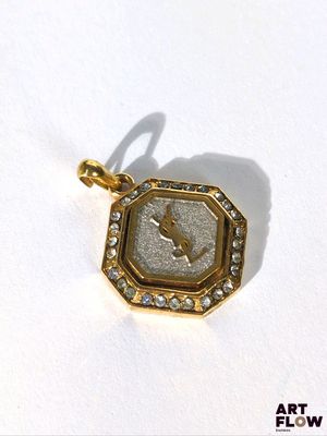 une image d'un pendentif plaqué or sur lequel figure une horloge