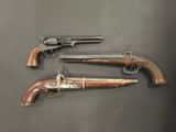 two pistols with wooden grips and brass handles on a black background